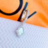 CZ huggie hoop earring with dangling MOF hamsa shape in a halo setting.
